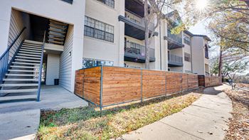 a wooden privacy fence in front of an apartment building  at Carmel Creekside, Texas